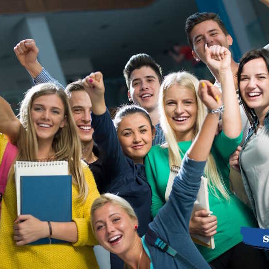 Група радісних підлітків-абітурієнтів святкує успіх, піднявши вгору кулаки та тримаючи в руках навчальні зошити -TechnikumSTN