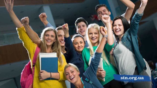 Група радісних підлітків-абітурієнтів святкує успіх, піднявши вгору кулаки та тримаючи в руках навчальні зошити -TechnikumSTN
