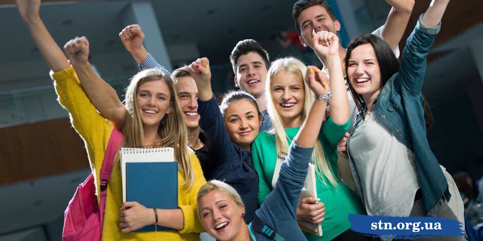 Група радісних підлітків-абітурієнтів святкує успіх, піднявши вгору кулаки та тримаючи в руках навчальні зошити -TechnikumSTN